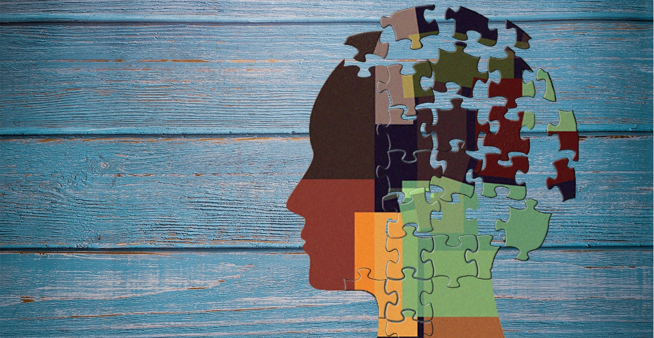 Puzzle-piece head silhouette on weathered blue wood — Therapy and Assessment